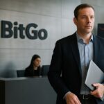 Bedrijfslobby met BitGo-logo op de wand en een medewerker die richting de camera loopt