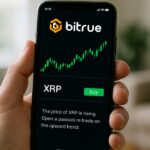 Hand met smartphone die de Bitrue-app toont met een groene XRP-koersgrafiek en een uitlegvenster