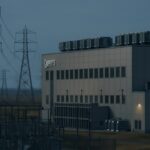 Groot datacenter met hoogspanningsleidingen en transformatorstations in de schemering