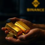 Handen houden gouden staven vast met op de achtergrond een scherm met het Binance-logo