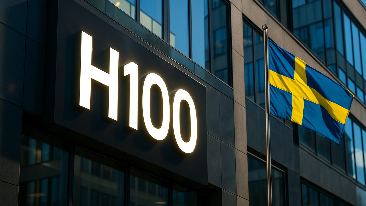 Het logo van het Zweedse bedrijf H100 op een gebouwgevel met een Zweedse vlag ernaast