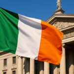 De Ierse vlag wappert voor een klassiek overheidsgebouw in Dublin onder een heldere hemel