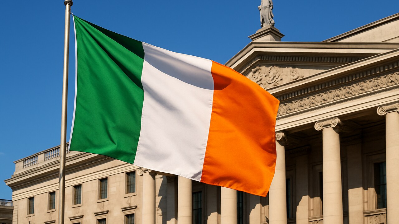 De Ierse vlag wappert voor een klassiek overheidsgebouw in Dublin onder een heldere hemel