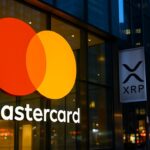 Het Mastercard-logo groot verlicht op een gebouwgevel, met een XRP-symbool ernaast