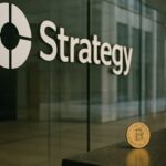 Logo van Strategy op een glazen kantoorwand met een fysieke Bitcoin-munt op een balie