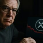 Een oudere man kijkt sceptisch naar de camera achter een laptop met het XRP-logo en een dalende rode grafieklijn.