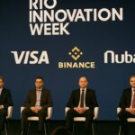 Paneldiscussie op een groot podium tijdens Rio Innovation Week met bedrijfslogo's op het scherm erachter