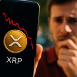 Smartphone toont het XRP-logo met een rode dalende koersgrafiek