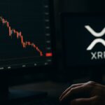 Handelsscherm met een dalende rode XRP-grafiek en het XRP-logo op een tweede monitor