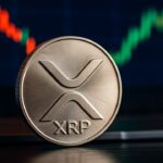 Een fysieke XRP-munt met het Ripple-logo voor een beeldscherm met een koersgrafiek die van rood naar groen kantelt.