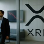 Kantoorlobby met XRP-logo op glazen wand en een scherm met dalende rode koerslijn op de achtergrond