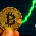 Fysieke Bitcoin-munt voor een scherm met een stijgende groene koersgrafiek en prijsniveaus