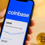 Smartphone met het Coinbase-logo en een leeninterface, met een fysieke Bitcoin-munt ernaast
