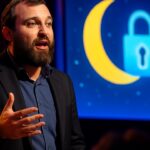 Charles Hoskinson spreekt op een podium over privacyproject Midnight met een scherm met maan en slotsymbool op de achtergrond