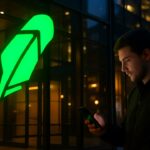 Groot Robinhood-logo op een gevel met een voorbijganger die op zijn telefoon een stijgende groene grafiek bekijkt