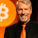 Michael Saylor met oranje stropdas op een podium voor een groot oranje Bitcoin-logo