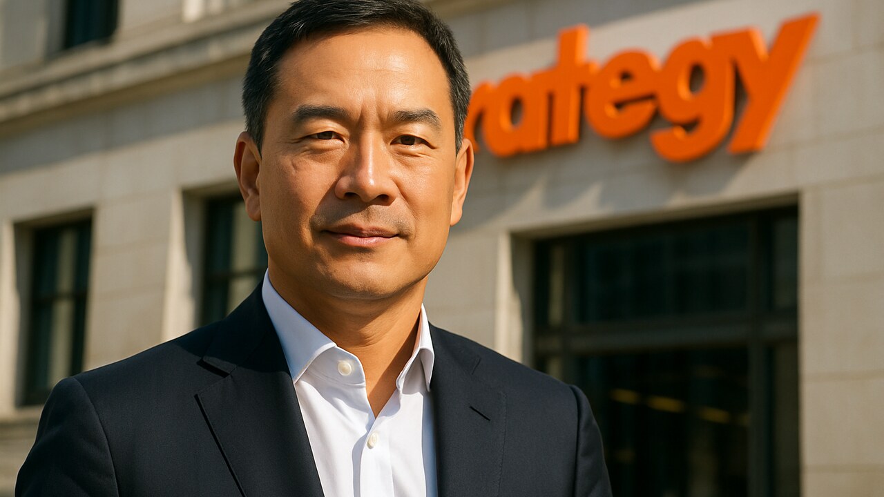 Phong Le, CEO van Strategy, voor een gevel met het oranje Strategy-logo