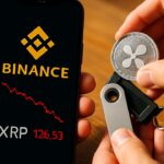 Een telefoon met het Binance-logo en fysieke XRP-munten die in een hardware wallet worden gelegd