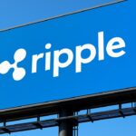Het Ripple-logo groot en herkenbaar op een digitaal buitenscherm tegen een blauwe lucht