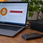 Laptop en mini-pc op een plank thuis, met op het scherm Bitcoin Core en een rode foutmelding na een crash