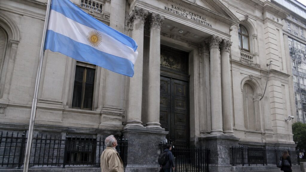 Gevel van de Argentijnse centrale bank in Buenos Aires met een wapperende Argentijnse vlag op de voorgrond