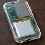 Achterkant van een doorzichtige hardware wallet vol epoxy, met printplaat, chip en accu zichtbaar