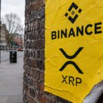 Geel reclameaffiche met het Binance-logo en het XRP-logo op een bakstenen muur, met een loslatende hoek