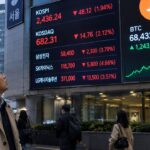 Groot elektronisch koersbord in Seoul met rode Koreaanse aandelenkoersen naast een Bitcoin-logo met een groene lijn, terwijl voorbijgangers omhoog kijken