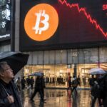 Groot reclamescherm in een regenachtige winkelstraat toont het Bitcoin-logo met een steil dalende rode koerslijn, terwijl een voorbijganger met paraplu omhoog kijkt