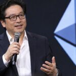 Tom Lee, voorzitter van BitMine, spreekt op een cryptoconferentie voor een groot Ethereum-logo