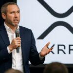 Spreker op een fintechcongres met het XRP-logo groot op het scherm achter hem