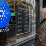 Etalage van een gokwinkel met een groot blauw Cardano-logo op het raam en een man die het quoteringsbord bekijkt