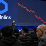 Groot scherm op een cryptoconferentie toont het Chainlink-logo naast een dalende rode koersgrafiek, met publiek op de voorgrond