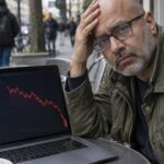 Kale man met grijze baard zit op een terras achter een laptop met het Ethereum-logo en een scherp dalende rode koersgrafiek