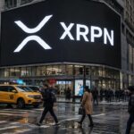 Groot reclamescherm op een straathoek in Manhattan met het XRP-logo en de letters XRPN, met voetgangers op straat