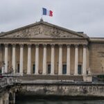 De Franse vlag wappert boven het Palais Bourbon, zetel van de Assemblée nationale in Parijs, op een bewolkte middag