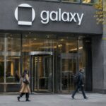 Gevel van een kantoortoren in New York met een groot Galaxy-logo boven de ingang op een bewolkte herfstmiddag