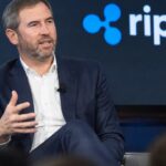 Ripple-CEO Brad Garlinghouse spreekt op een podium met een groot Ripple-logo op het scherm achter hem