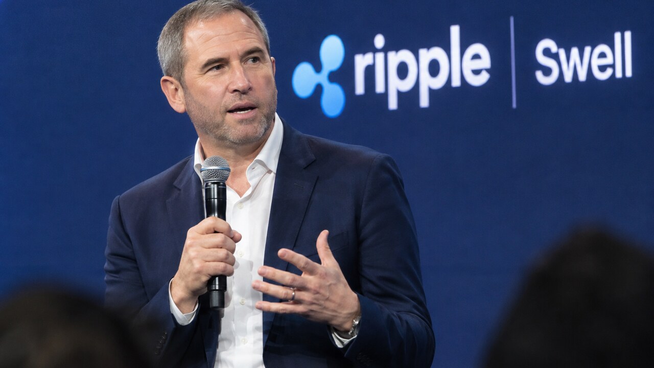 Ripple-CEO Brad Garlinghouse spreekt op het podium van de Swell-conferentie met het Ripple-logo op de achtergrond