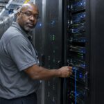Technicus sluit een kabel aan in een datacenter met serverracks, met een groot Ethereum-logo op de voorste rack
