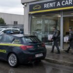 Agenten van de Italiaanse financiële politie dragen bewijsdozen naar buiten bij een autoverhuurbedrijf aan de rand van Milaan