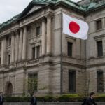 Hoofdkantoor van de Bank of Japan in Tokio met de Japanse vlag ervoor en voorbijgangers op straat