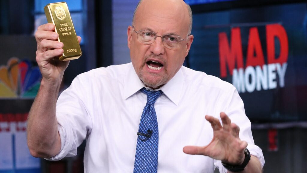 Jim Cramer houdt in een televisiestudio een goudstaaf omhoog terwijl hij geanimeerd praat