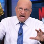 Jim Cramer houdt in een televisiestudio een goudstaaf omhoog terwijl hij geanimeerd praat