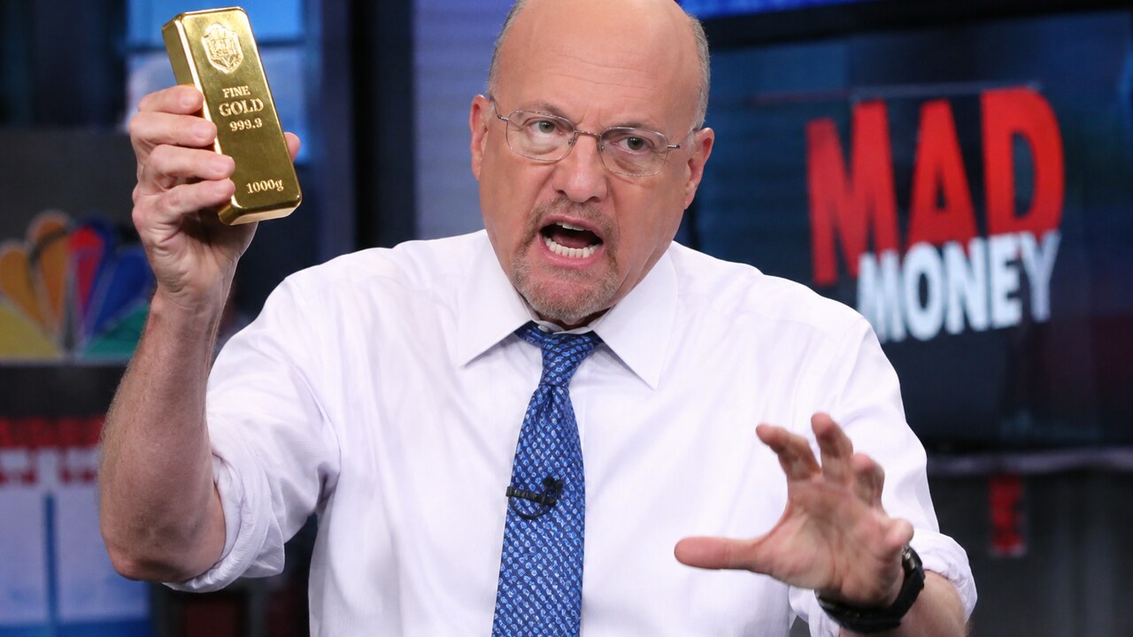 Jim Cramer houdt in een televisiestudio een goudstaaf omhoog terwijl hij geanimeerd praat