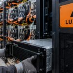 Technicus schuift een AI-server in een rack met Luxor-logo, met daarachter een rij Bitcoin-mijnbouwmachines in een datacenter