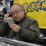Verzamelaar bekijkt een gewaardeerde Pokémonkaart met een loep op een kaartenbeurs, met een groot Pokémon-logo op de achtergrond