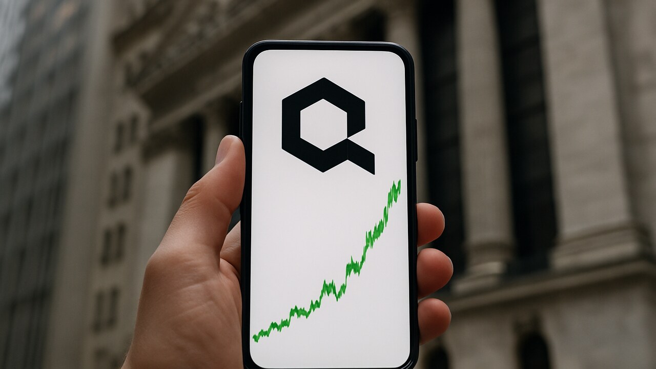 Hand houdt smartphone met stijgende Quant-koersgrafiek voor een bankgebouw in New York