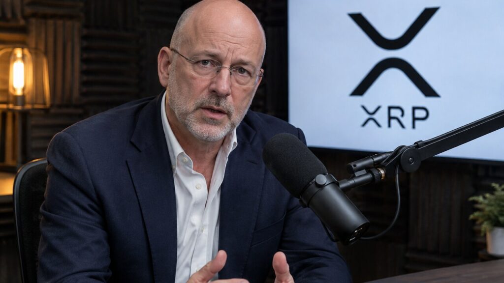Man met bril spreekt in een podcaststudio in een microfoon, met het XRP-logo op een scherm achter hem