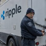 Beveiliger sluit een zware ketting met hangslot om de achterdeuren van een bevroren waardetransportwagen met Ripple-logo